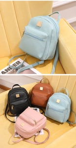 Dettaglio di mini zaini in ecopelle blu, nero, marrone e rosa con targhette in metallo