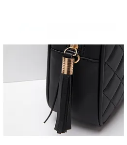 Detail of black quilted shoulder bag featuring gold ring zipper and leather fringe tassel