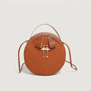 Classic round brown leather shoulder bag with woven texture and gold flamingo charm