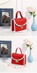 Close-up of red quilted handbag featuring white contrast piping and gold metal clasp