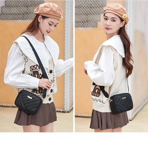 Detail of black quilted crossbody bag with gold hardware and adjustable wide strap