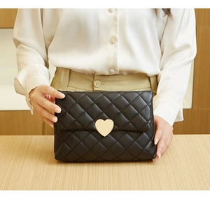 Close-up of black quilted handbag featuring a golden heart-shaped metal clasp and stitching