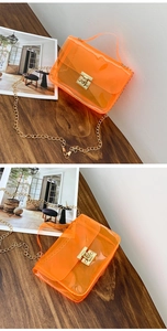 Detail of bright orange transparent PVC jelly bag with gold chain strap and metal lock
