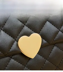 Close-up of heart-shaped gold metal hardware on black quilted leather handbag