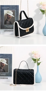 Close-up of black quilted leather bag with white trim and golden twist lock detail