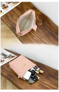Close-up of pink quilted crossbody bag interior holding phone, wallet and cosmetics