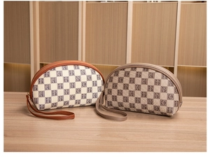 Detail view of semi-circular makeup bags with letter grid pattern and leather handles