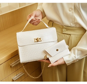 Detail of white crocodile pattern handbag with gold clasp and matching mini wallet
