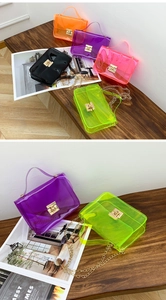 Macro view of clear PVC jelly bag featuring a gold metal lock and chain strap detail
