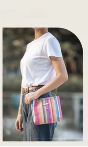Close-up of rainbow woven shoulder bag with gold flamingo charm and elegant chain strap