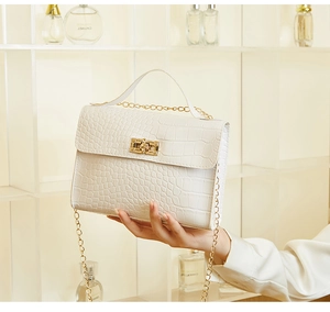 Detailed view of white crocodile texture leather handbag with gold metal twist lock