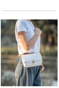 Close-up of white quilted crossbody bag with gold metal lock worn by a model outdoors