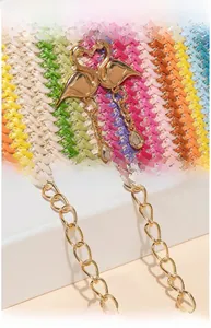 Detail of rainbow woven bucket bag featuring gold swan pendant and metallic chain strap
