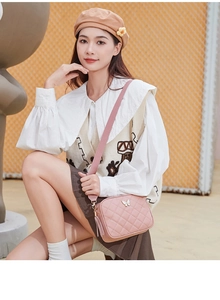Pink quilted shoulder bag featuring metal butterfly detail and tassels worn by a model