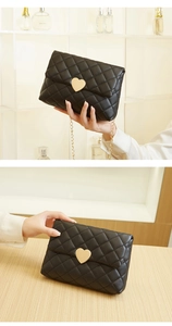 Detail of black quilted crossbody bag featuring a golden heart-shaped lock and chain