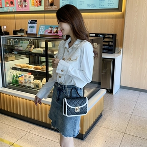 Quilted leather flap bag with chain strap and contrast piping in a cafe setting