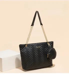 Detail of black quilted tote bag with golden chain strap and round coin purse