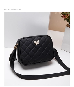 Detail of black quilted crossbody bag with white butterfly motif and tassel zipper