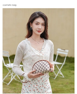 Chic beige canvas cosmetic bag with brown leather trim held by a model on a lawn