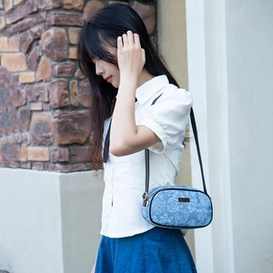Blue denim floral shoulder bag with rose pattern and metal plaque shown on model