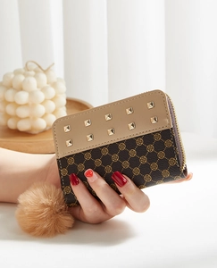 Detail of mini rivet wallet featuring clover pattern and plush pompom keychain