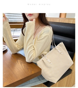 Detail of a large cream tote bag with yellow circular patterns on a shoulder strap