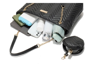 Detail of black quilted tote bag capacity showing tablet, smartphone and daily items