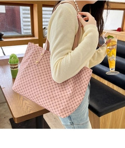 Pink tote bag detail with circular patterns and gold metal studs in a warm cafe setting