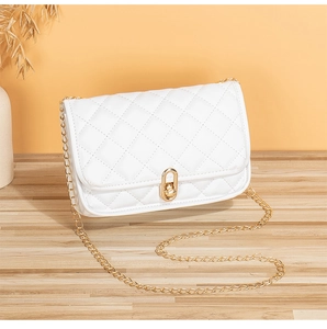 Detailed view of white quilted faux leather texture and gold twist-lock on handbag