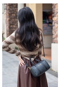 Outdoor shot of checkered Boston bag with leather straps and gold metal details