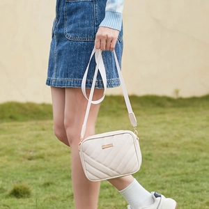 Minimalist white quilted crossbody camera bag with wide strap and gold hardware detail