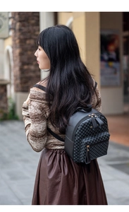 Detail view of mini backpack featuring geometric pattern fabric and golden zippers