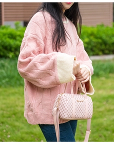 Pink Boston bag with monogram pattern held by a model in a casual spring outfit