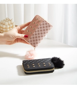 Close-up of leather wallets with monogram prints, metal studs and pompom charms
