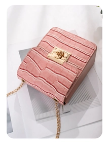 Close-up of pink faux crocodile leather shoulder bag with gold chain and metal lock