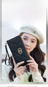 Detail of black quilted long wallet with golden double ring buckle and wrist strap