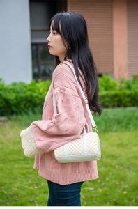 Outdoor lifestyle shot of a white Boston bag with yellow logo print and shoulder strap