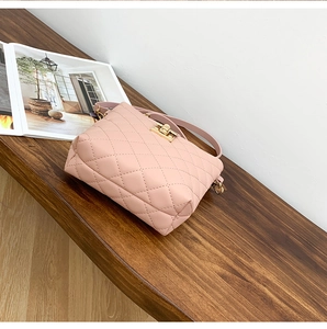 Detail of pink quilted bucket bag featuring a gold-tone twist lock and PU leather texture