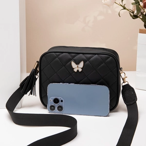 Black quilted crossbody bag with butterfly clasp and wide woven strap shown with phone