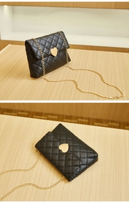 Detail of black quilted leather crossbody bag featuring a golden heart-shaped clasp