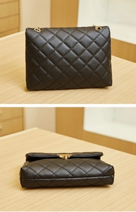 Detail view of black quilted flap bag with golden heart-shaped clasp and metal chain strap