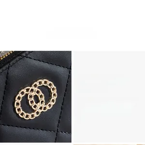 Close-up of golden interlocking rings on black quilted leather wallet surface