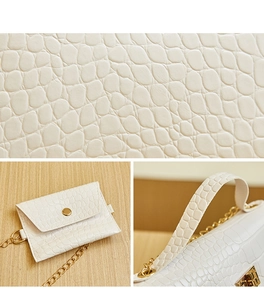 Detail of white crocodile embossed faux leather texture and gold hardware on handbag