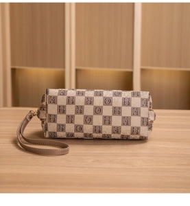 Detail view of rectangular checkered pouch with letter prints and brown wristlet strap