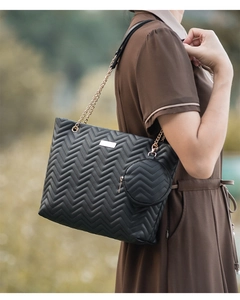 Outdoor shot of a black wave quilted tote bag with gold chain strap and matching coin pouch