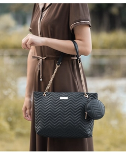 Close-up of black quilted tote bag with wave stitching detail and round coin purse