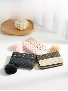 Detailed view of mini rivet purses with vintage patterns and fluffy faux fur pompons