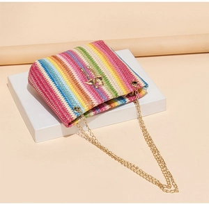 Detail of colorful woven straw bucket bag with gold angel charm and chain strap