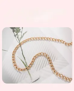 Detail of high-gloss gold metal chain strap with flat O-ring links for crossbody bag