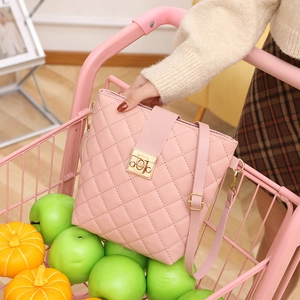 Pink quilted crossbody bucket bag with gold clasp shown in a creative shopping cart